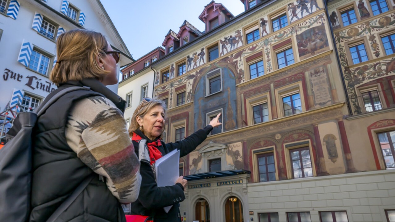 Guide Hanny weist auf die historischen Fassadenbemalungen in der Stadt hin. 