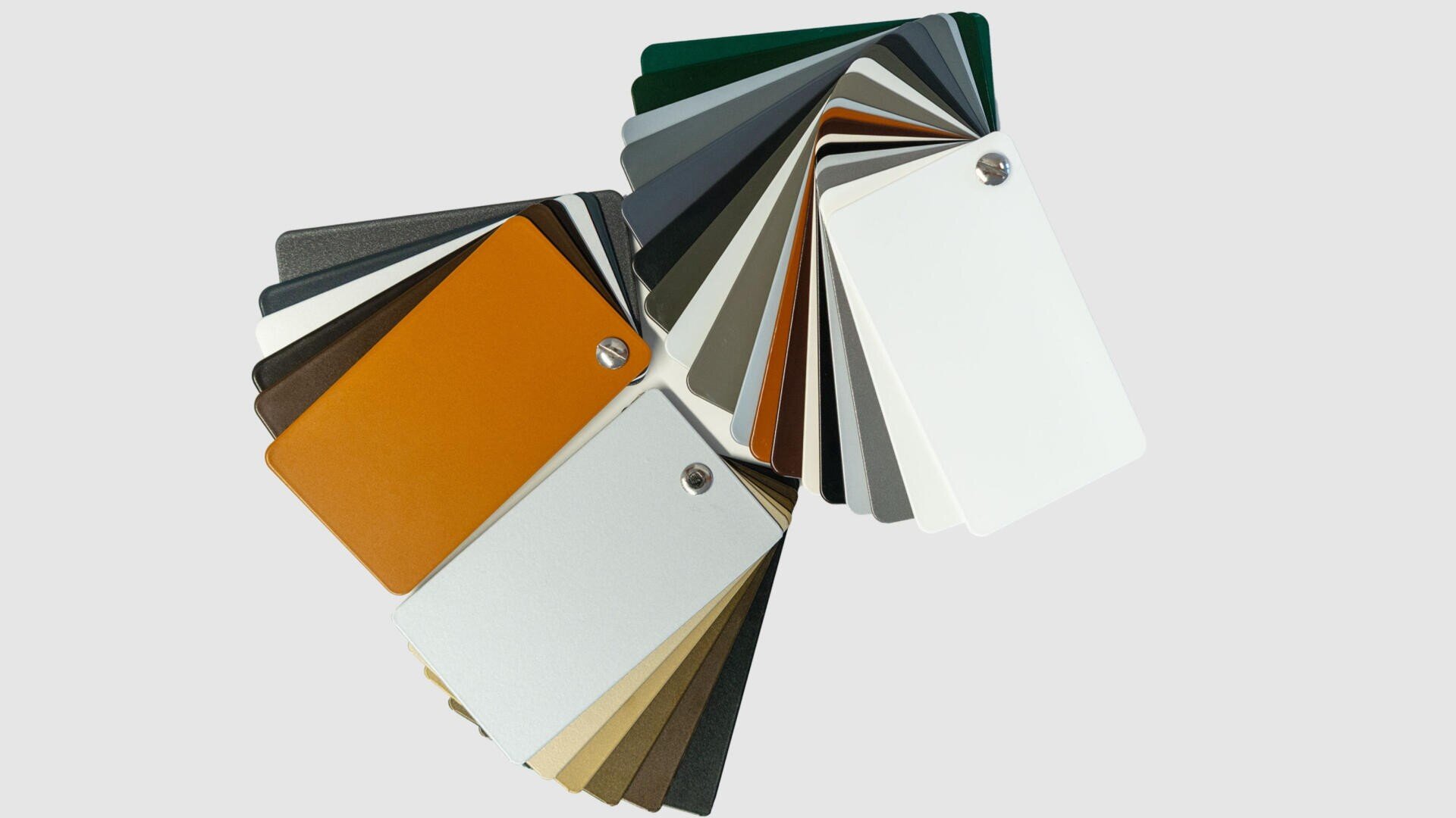 Zwei aufgefächerte Sätze rechteckiger Farbfelder, die jeweils durch eine Metallniete zusammengehalten werden, zeigen eine Vielzahl von Farben, darunter Weiß, Orange, Braun, Schwarz, Grau, Grün und Gold auf einem hellgrauen Hintergrund.