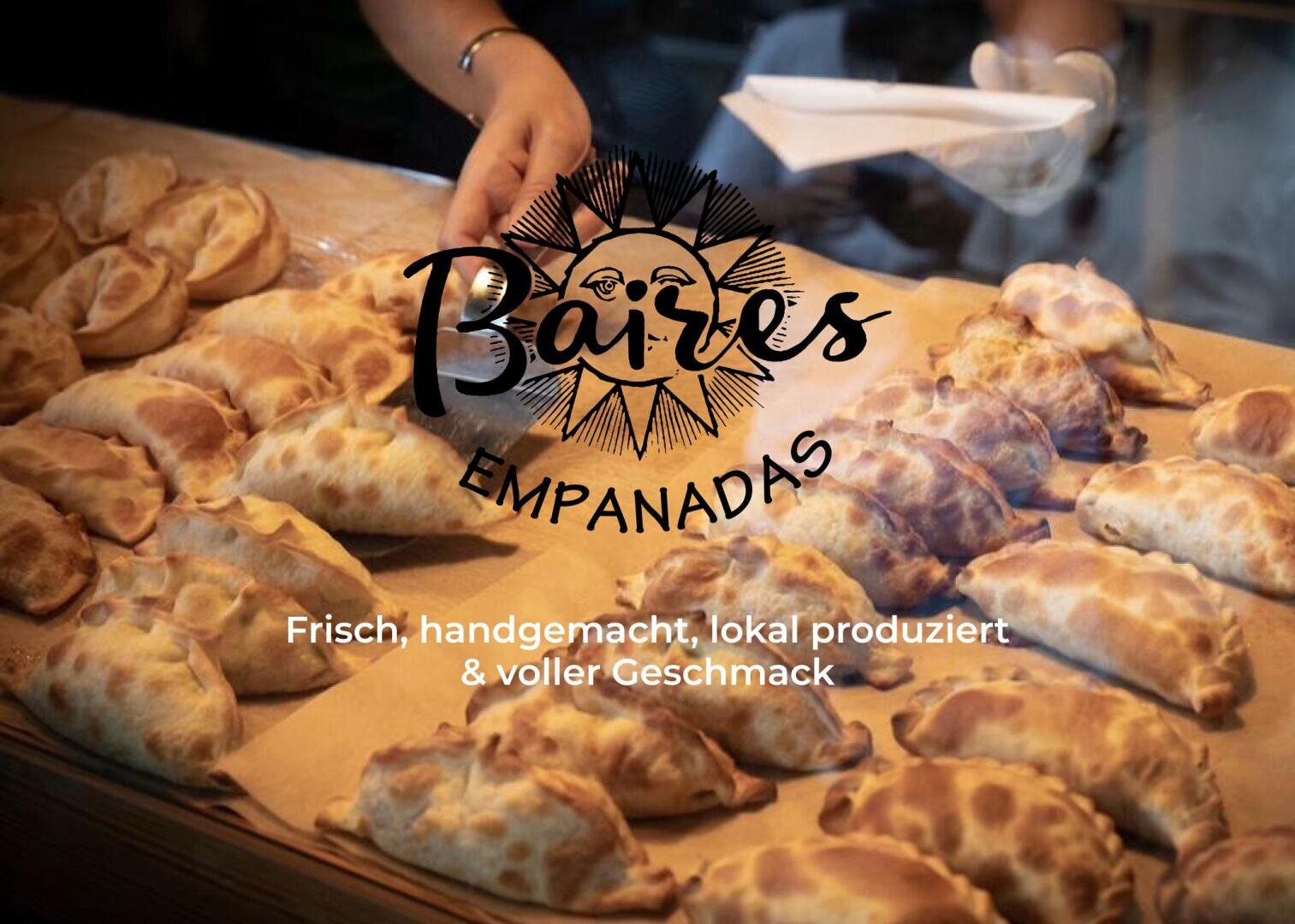 Eine Person arrangiert gebackene Empanadas auf einer Holztheke. Der Text lautet: Baires Empanadas. Frisch, handgemacht, lokal produziert & voller Geschmack.
