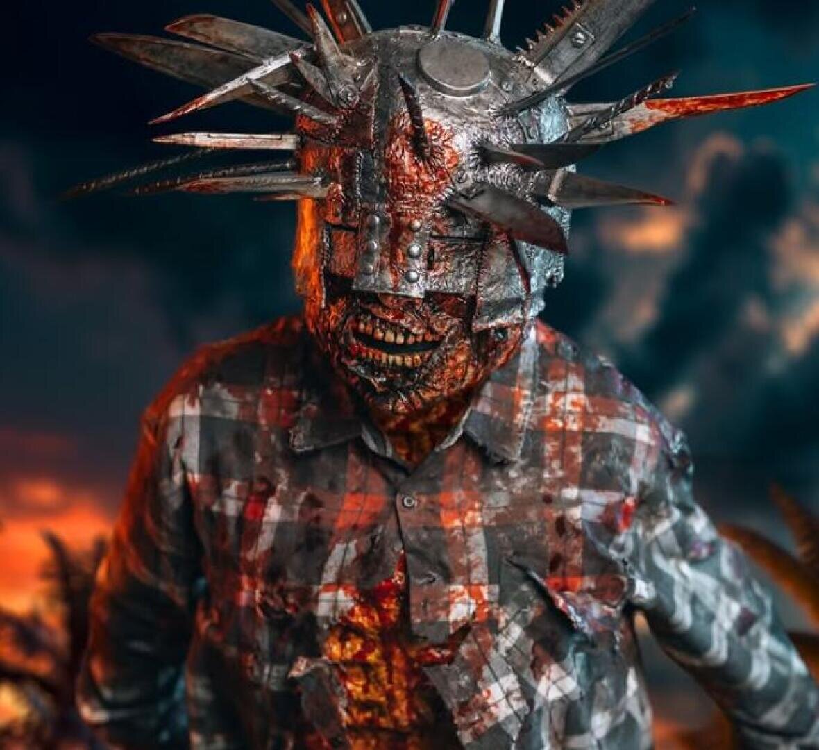 Eine Person mit einem Metallhelm, aus dem große, scharfe Stacheln und Sägeblätter herausragen, bekleidet mit einem blutverschmierten, zerrissenen karierten Hemd, steht vor einem dramatischen Sonnenuntergangshimmel.