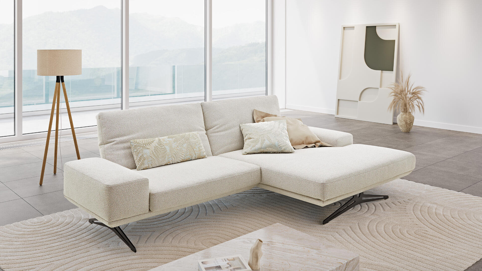 Modernes Wohnzimmer mit einem weißen Ecksofa, Kissen in neutralen Farbtönen, einer Stehlampe, abstrakter Wandkunst, Pampasgras in einer Vase, einem runden, strukturierten Teppich und großen Fenstern, die einen malerischen Blick auf die Berge bieten.