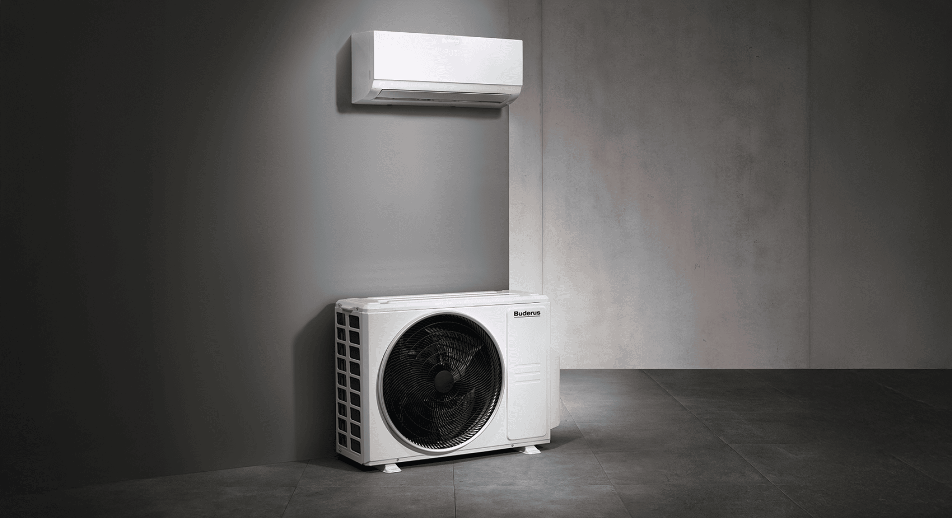 Eine moderne Split-Klimaanlage ist an einer grauen Wand montiert, mit dem Innengerät darüber und dem Außengerät darunter, beide in einem minimalistischen, modernen Raum.