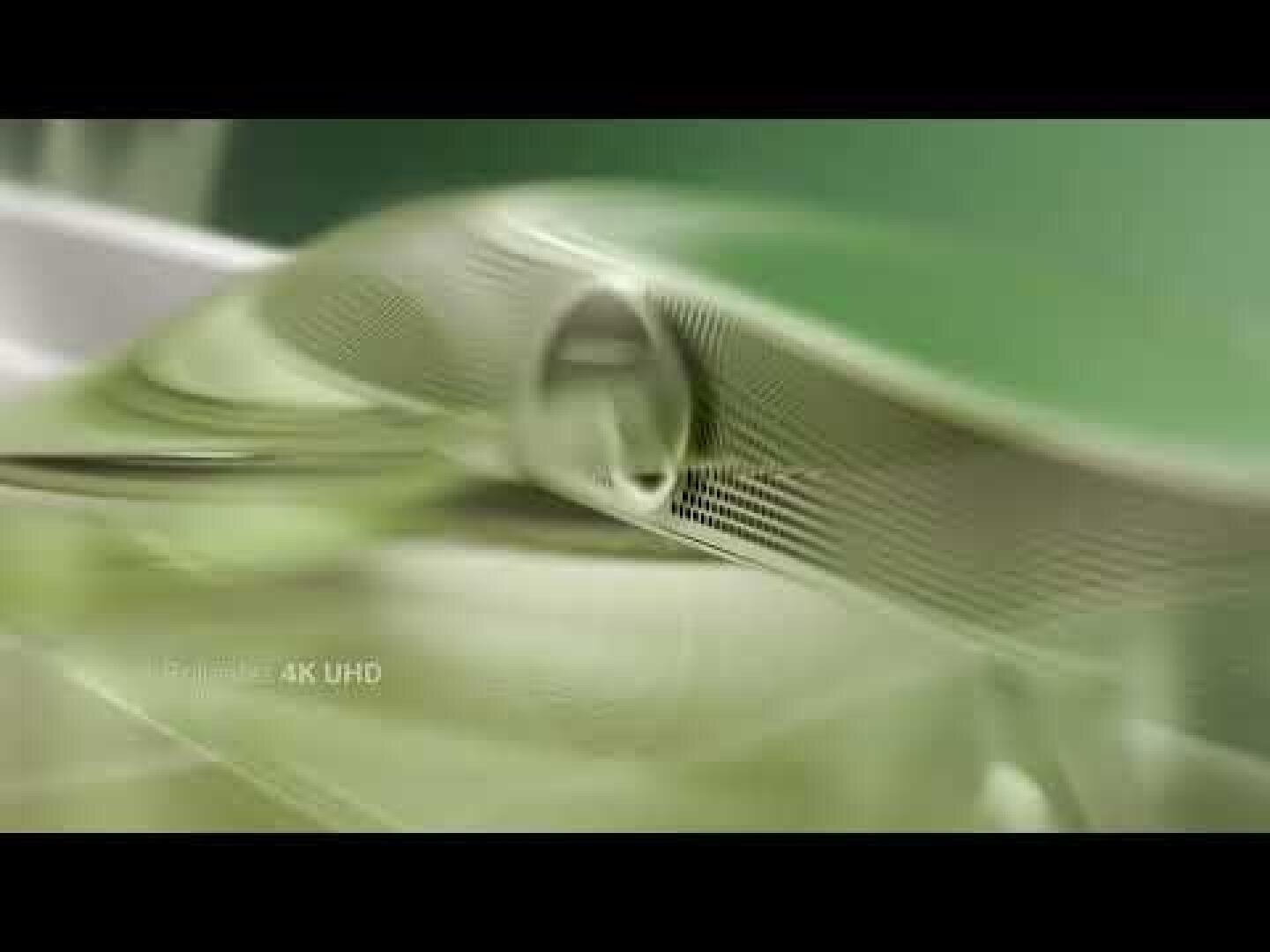 Abstraktes Bild mit glatten, durchscheinenden grünen und weißen Wellen mit sanften Kurven, die ein fließendes, futuristisches Design erzeugen. Der Schriftzug "Realism 4K UHD" erscheint schwach in der unteren linken Ecke.