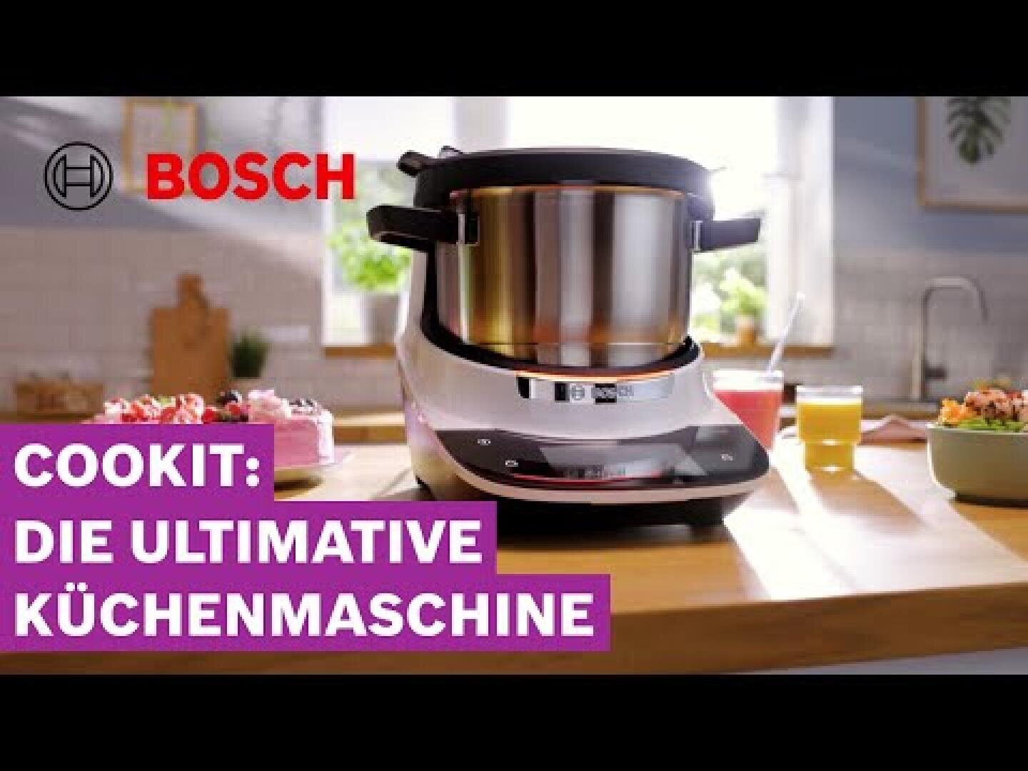 Eine Bosch-Küchenmaschine steht auf einer hölzernen Arbeitsplatte in einer hellen Küche. Der Text auf dem Bild lautet: COOKIT: DIE ULTIMATIVE KÜCHENMASCHINE. In der Ecke ist das Bosch-Logo zu sehen.