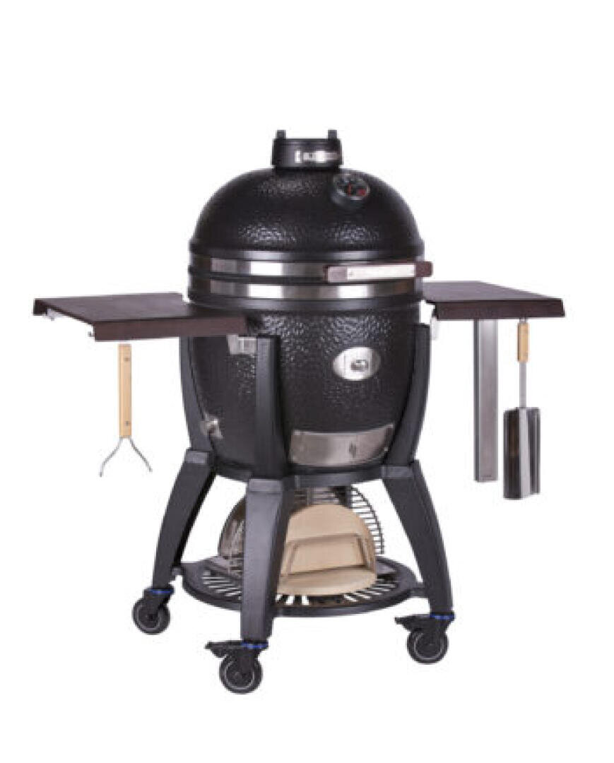 Schwarzer Kamado-Grill aus Keramik mit gewölbtem Deckel, Temperaturanzeige, Seitenablagen, Griffen und an Haken hängenden Grillwerkzeugen auf einem Metallgestell mit Rädern.