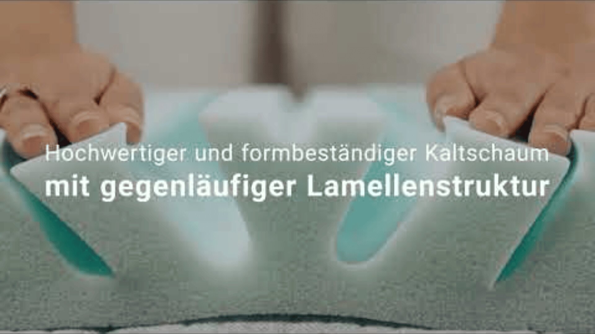 Die Hände drücken sich auf eine Schaumstoffmatratze mit Rillen. Der deutsche Text über dem Bild lautet: Hochwertiger und formbeständiger Kaltschaum mit gegenläufiger Lamellenstruktur.