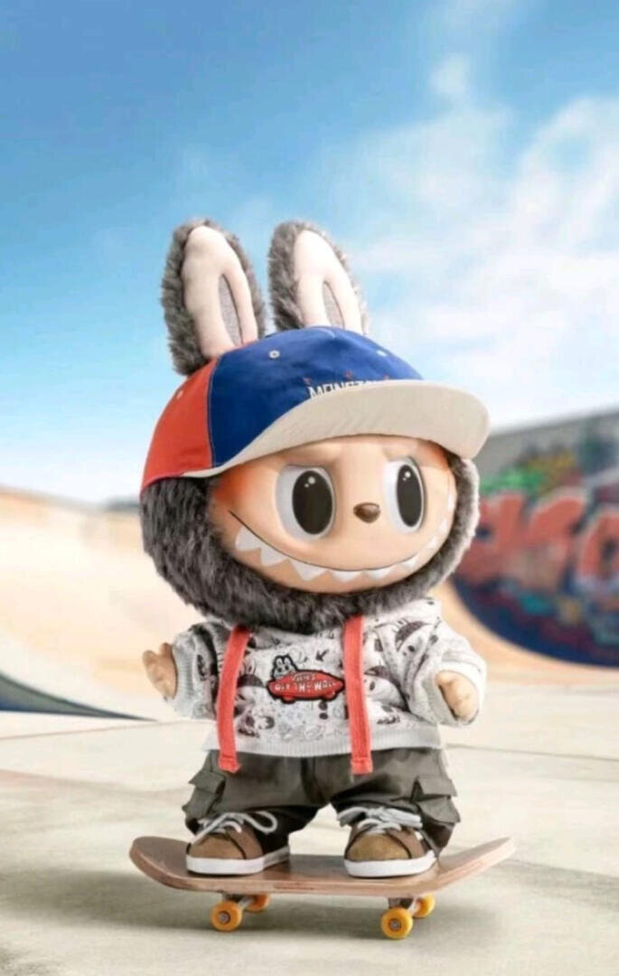 Eine niedliche, puppenähnliche Figur mit Hasenohren, einem breiten Lächeln und großen Augen trägt eine Kappe, einen Kapuzenpulli und Turnschuhe, während sie auf einem Skateboard in einem Skatepark mit Graffiti im Hintergrund steht.