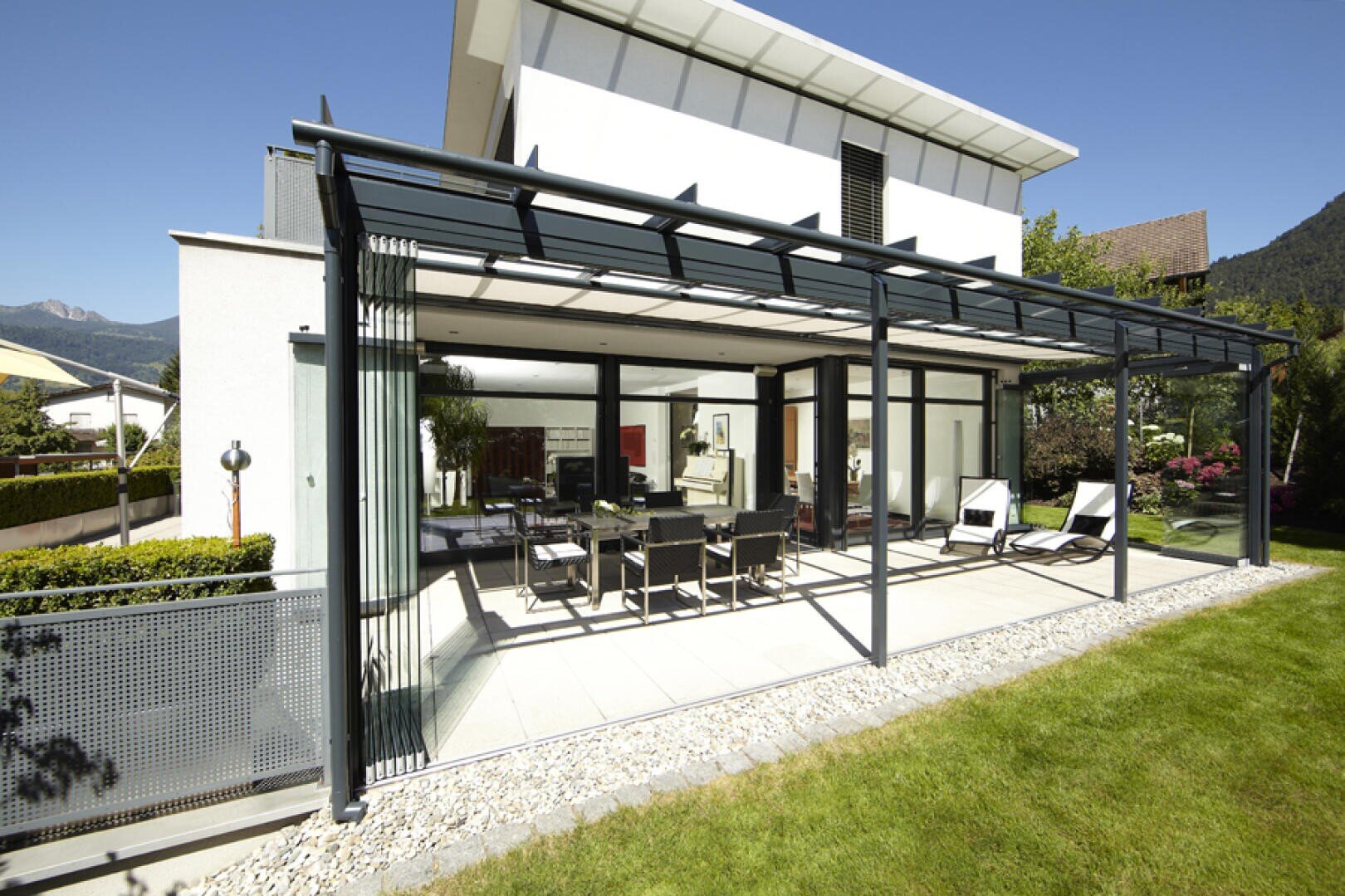 Ein Innenhof mit einer glasüberdachten Veranda und einem Rasen.