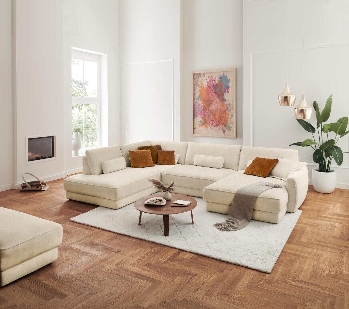 Ein modernes Wohnzimmer mit einem großen beigen Sektionssofa, braunen Kissen, einer hellen Decke, einem runden Couchtisch aus Holz, einem gemusterten Teppich, einem Holzboden, einer Topfpflanze, abstrakter Wandkunst und Pendelleuchten.