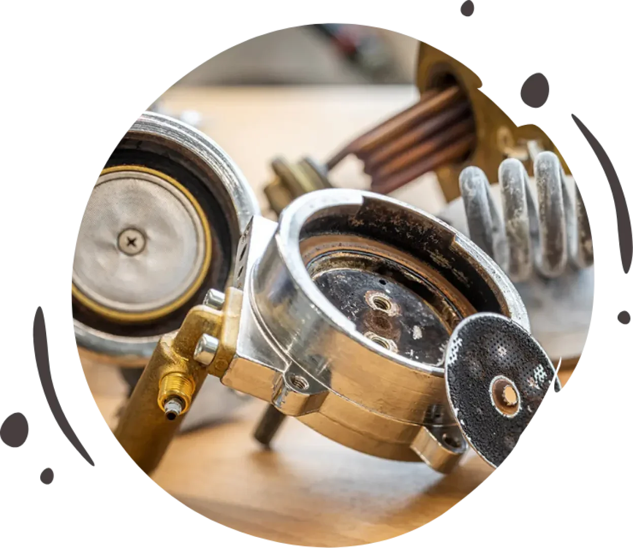 Nahaufnahme von demontierten Teilen einer Espressomaschine, darunter ein Siebträger, ein Duschsieb und Metallteile, die auf einer Holzfläche liegen.