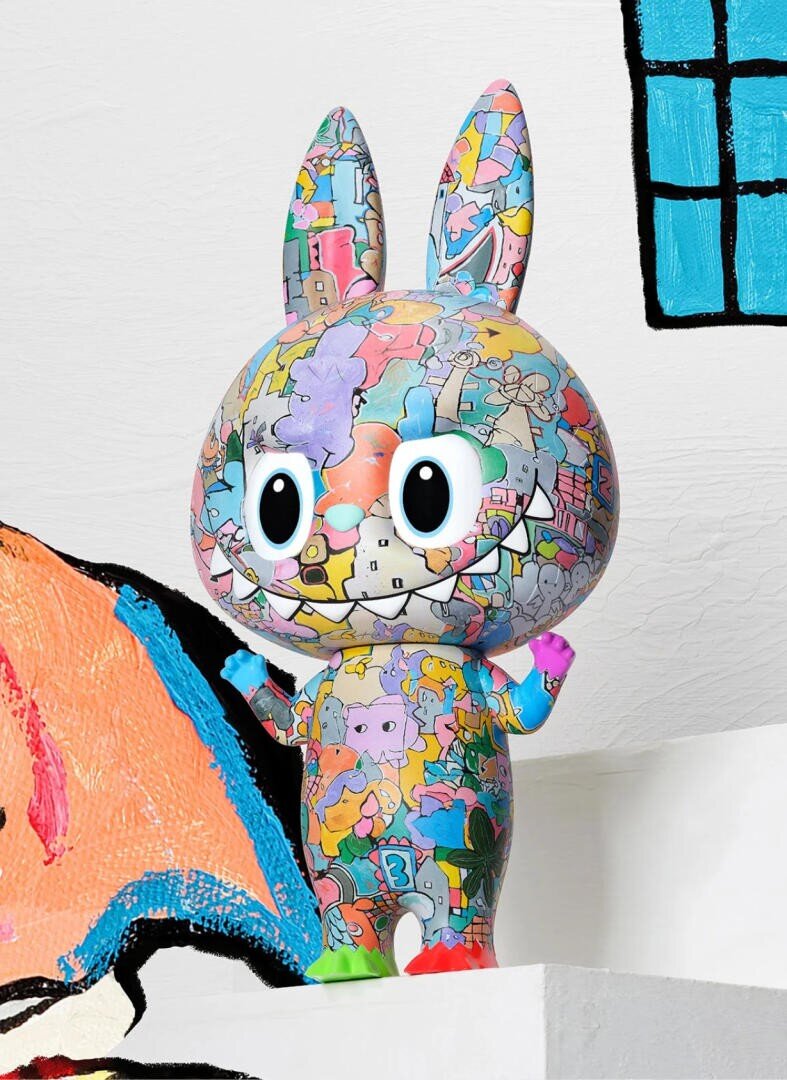 Eine bunte Cartoon-Hasenfigur steht auf einem weißen Podest. Seine Oberfläche ist mit lebhaften, puzzleartigen Mustern und skurrilen Figuren bedeckt. Der Hintergrund zeigt abstrakte gemalte Formen und einen blauen Fensterumriss auf einer weißen Wand.