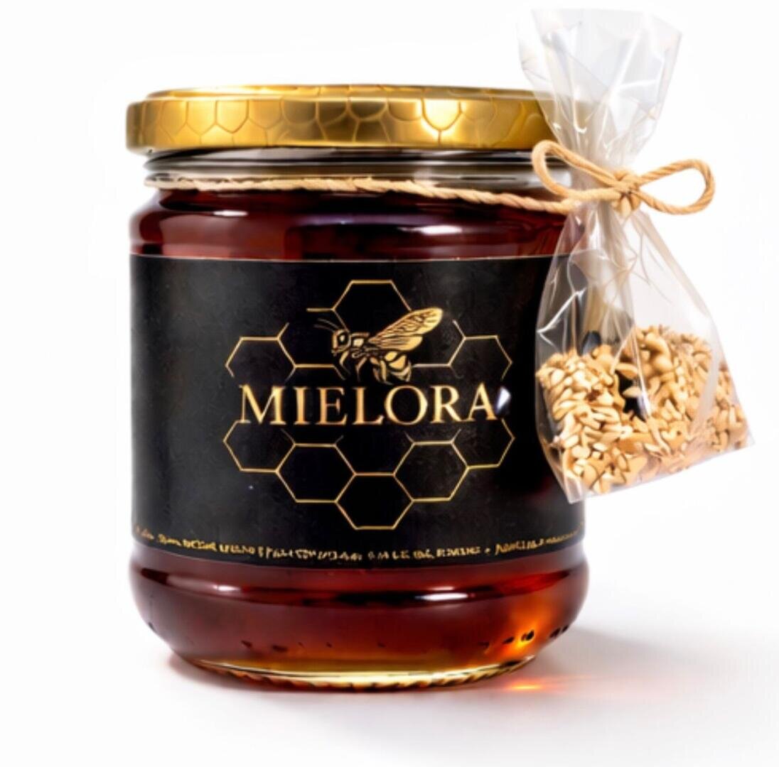 Ein Glas Mielora-Honig mit goldenem Deckel und einem schwarzen Etikett mit Waben- und Bienenmotiv. Neben dem Glas befindet sich ein kleines durchsichtiges Tütchen mit Samen, das mit einer Schnur verschnürt ist.