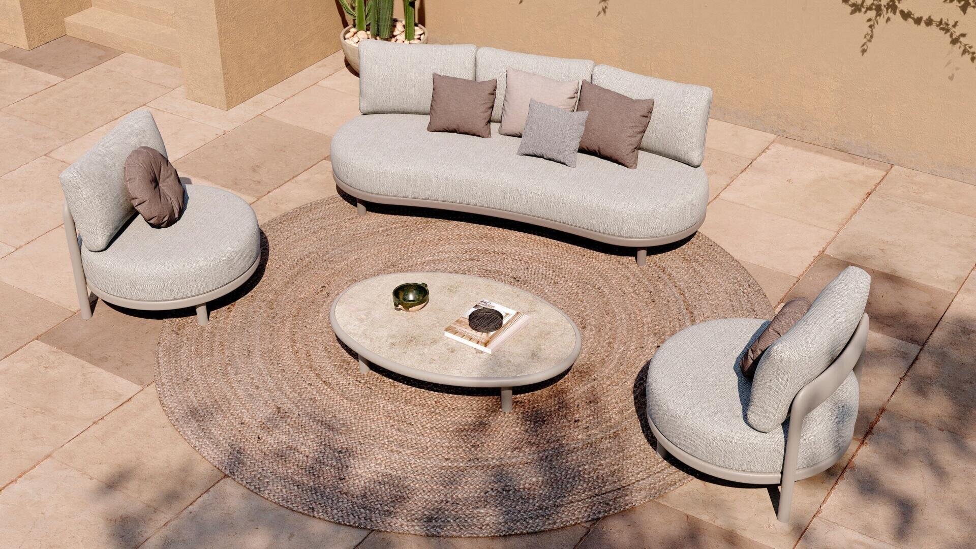 Ein geschwungenes hellgraues Sofa und zwei passende Stühle umgeben einen ovalen Couchtisch auf einem runden gewebten Teppich auf einer gefliesten Terrasse in neutralen Tönen. Kissen und Dekoartikel sorgen für Details.