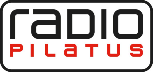 Rechteckiges Logo mit abgerundeten Ecken. „Radio“ ist in schwarzer, moderner Schrift geschrieben, während „PILATUS“ in Großbuchstaben und in roter Farbe darunter erscheint. Das Logo ist umrandet.