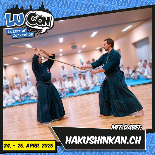Zwei Personen in Kampfsportuniformen demonstrieren eine Holzschwerttechnik in einem großen Dojo, während eine Gruppe von sitzenden Teilnehmern zusieht. Text enthält LUCON Luzerner Convention, Daten und hakushinkan.ch.