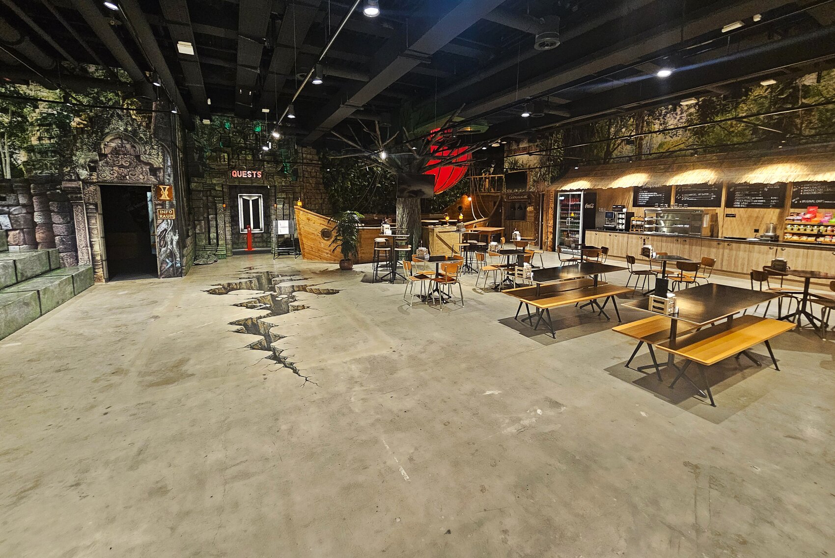 Ein geräumiges, dschungelartiges Restaurant mit Holztischen und -stühlen, einem rissigen Boden, üppigen Wanddekorationen und einem Tresen mit Speisekarten. Die Atmosphäre ist abenteuerlich und einladend.