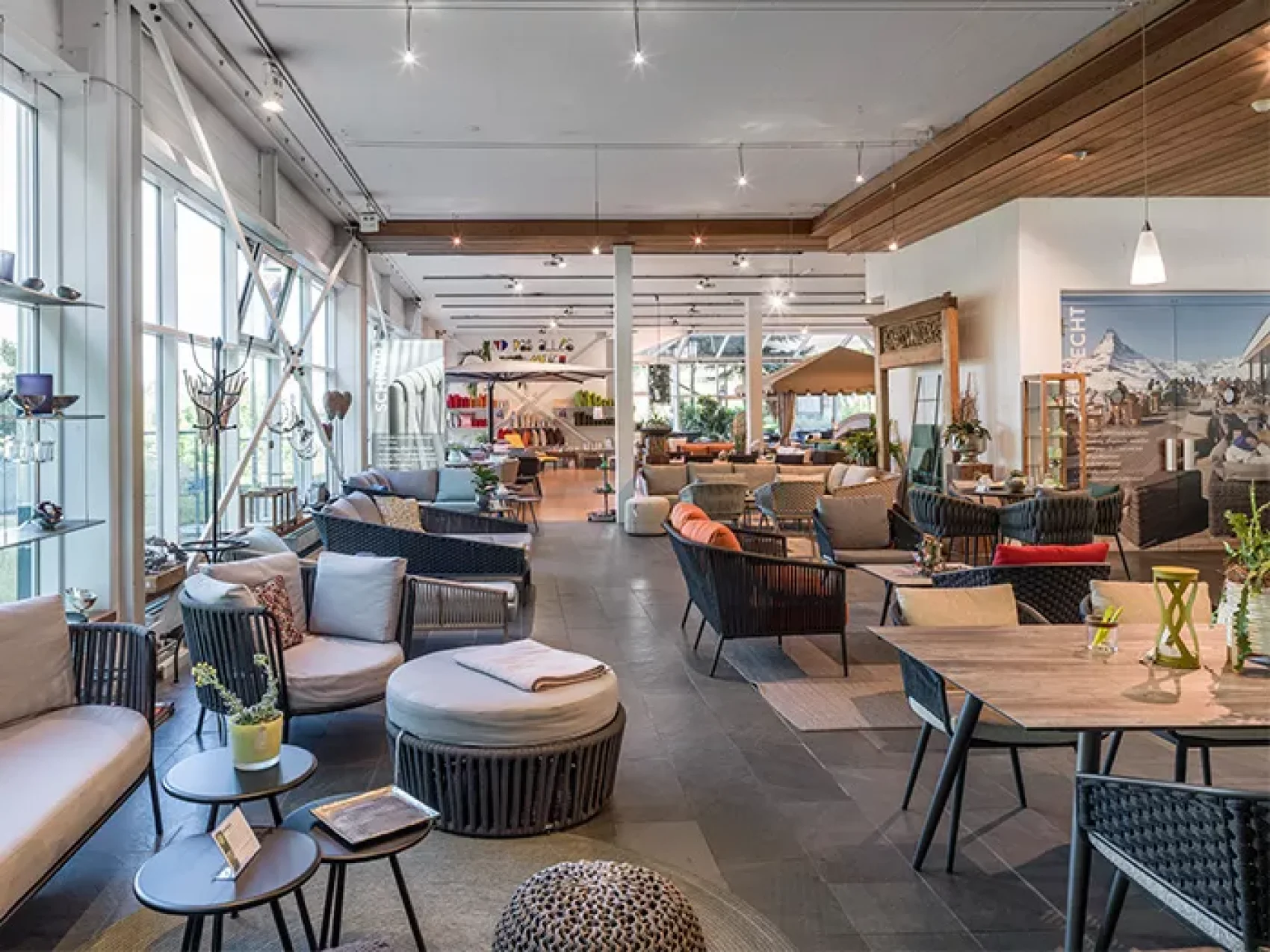 Ein geräumiger, moderner Möbel-Showroom mit großen Fenstern, in dem verschiedene Sofas, Stühle, Tische und Dekorationsstücke in einer gut beleuchteten, organisierten Anordnung ausgestellt sind.